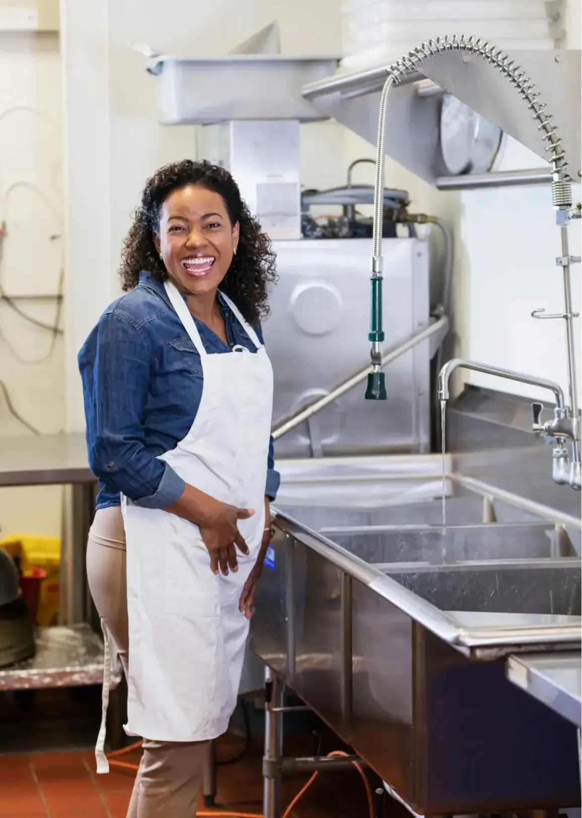 Smiling woman in apron working in a commercial kitchen.