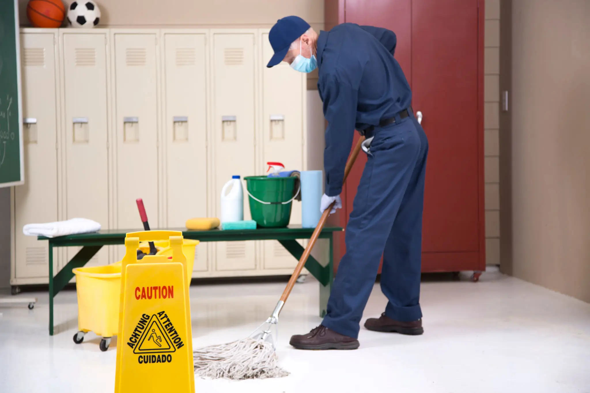 Janitor mopping a floor with caution signs nearby.