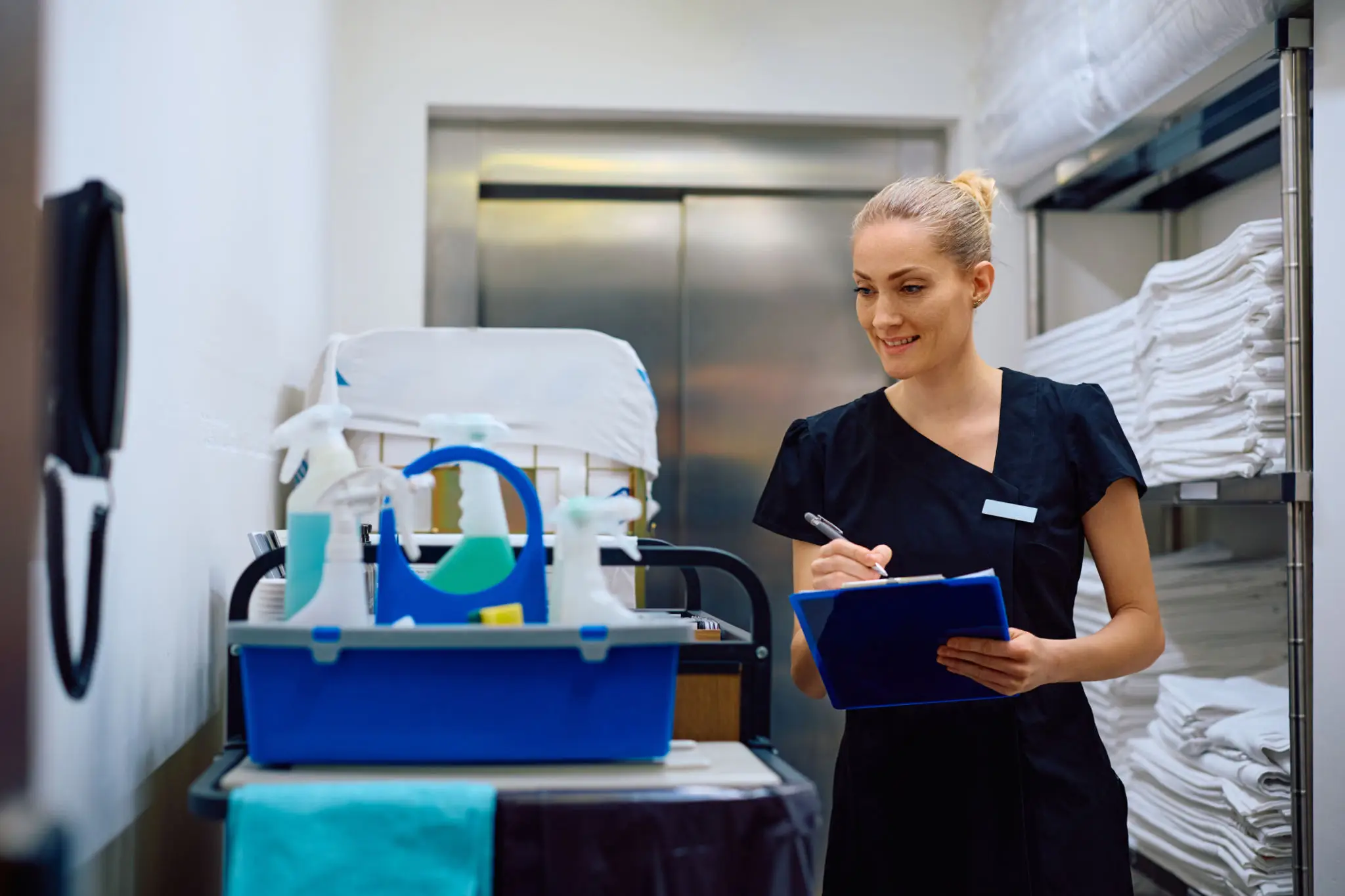 A healthcare professional writing notes beside medical equipment in a clinical setting.